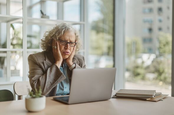 Senior businesswoman feeling stressed and worried looking at laptop