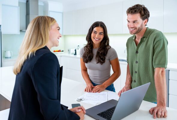 Real estate agent with couple looking at a laptop
