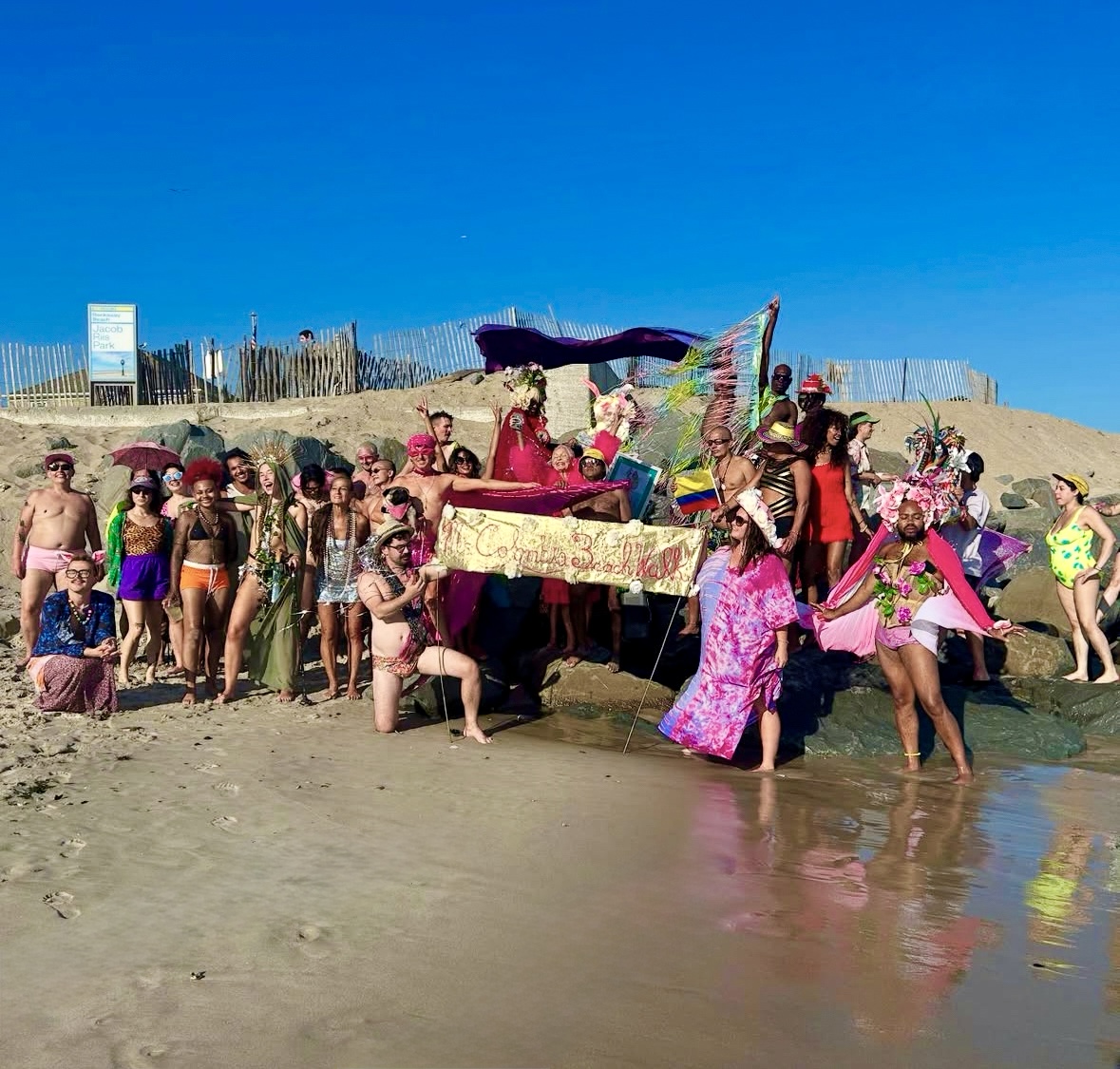 Community members gather on the rocks at Jacob Riis Beach on August 9, 2025, “Frocks on the Rocks” for Miss Colombia Day, an annual memorial honoring Miss Colombia, a beloved LGBTQIA+ icon who passed away at the beach in 2018.