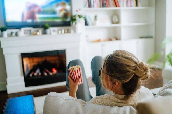 Home TV set and many channels. Rearview of woman eating popcorn and watching tv at home