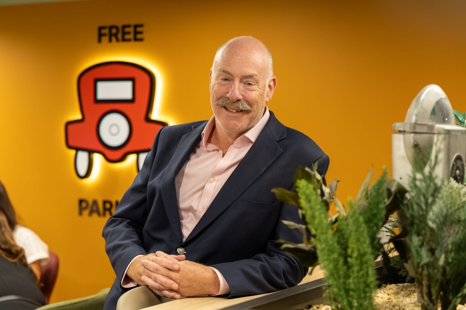 Giles Fuchs, Co-Founder of Office Space in Town (OSiT), smiling in front of a FREE PARKING sign.