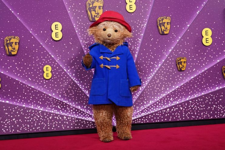 Paddington Bear in a blue duffle coat and red hat on a purple background with BAFTA and EE logos