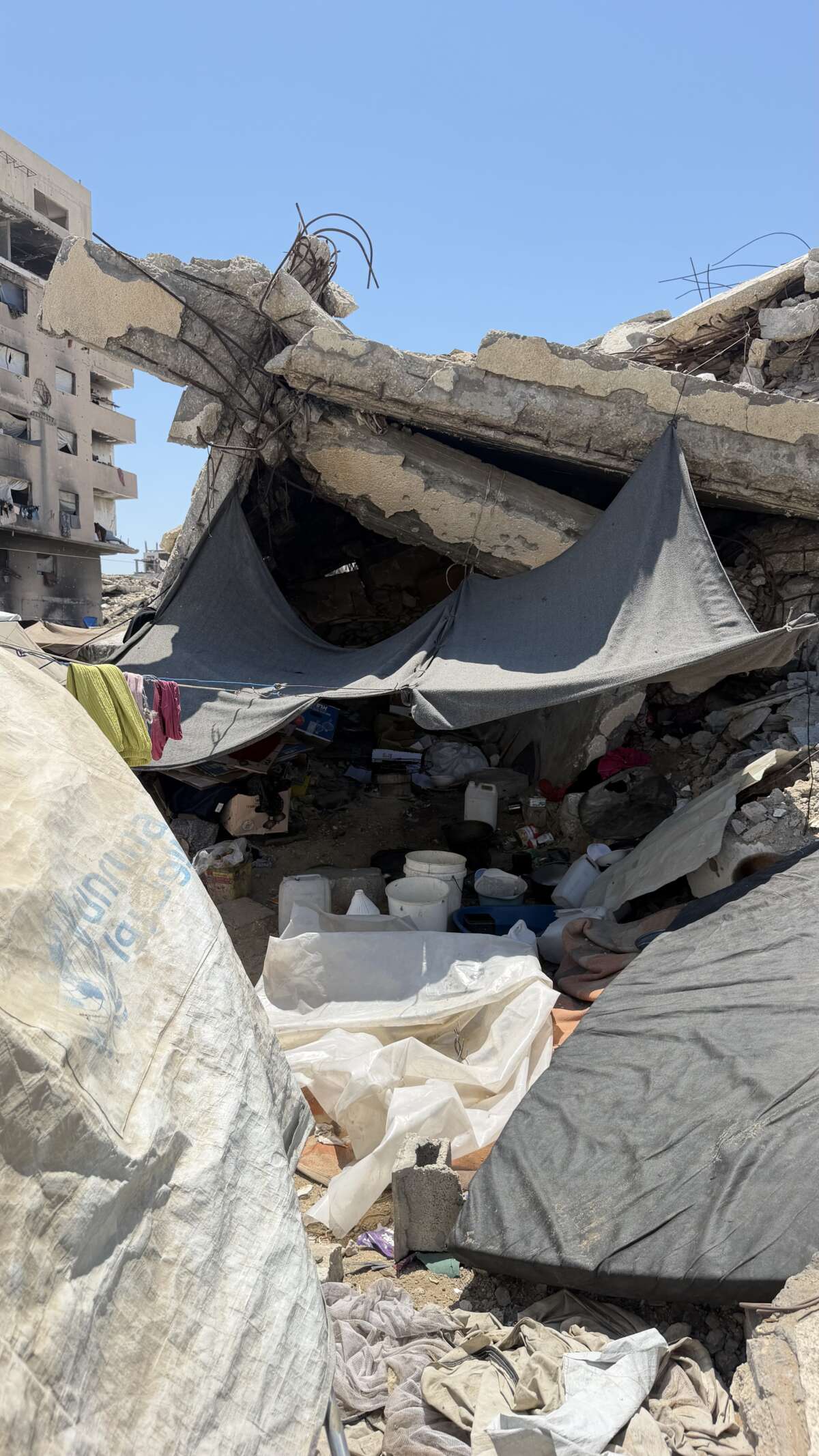 Walaa Al-Danaf, a 31-year-old widow and mother of five, cooks over an open fire inside a makeshift kitchen set up under the rubble of a destroyed building to save gas and afford essential supplies for her family in the west of Gaza.