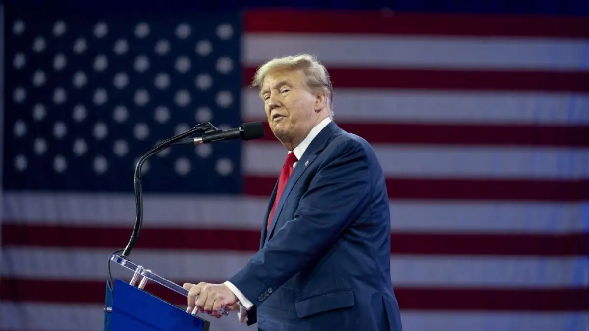 Donald Trump speaking at a podium in front of an American flag.