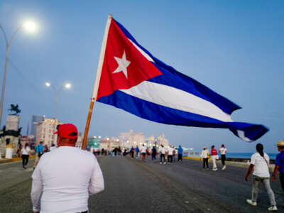 A man marches holding a Cuban national flag along Havana's waterfront to mark International Workers' Day at the AntiImperialist Platform in front of the U.S. Embassy in Havana, Cuba, on May 1, 2026.