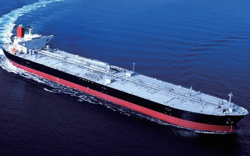 Aerial view of a large black and red crude oil tanker ship sailing through deep blue ocean waters
