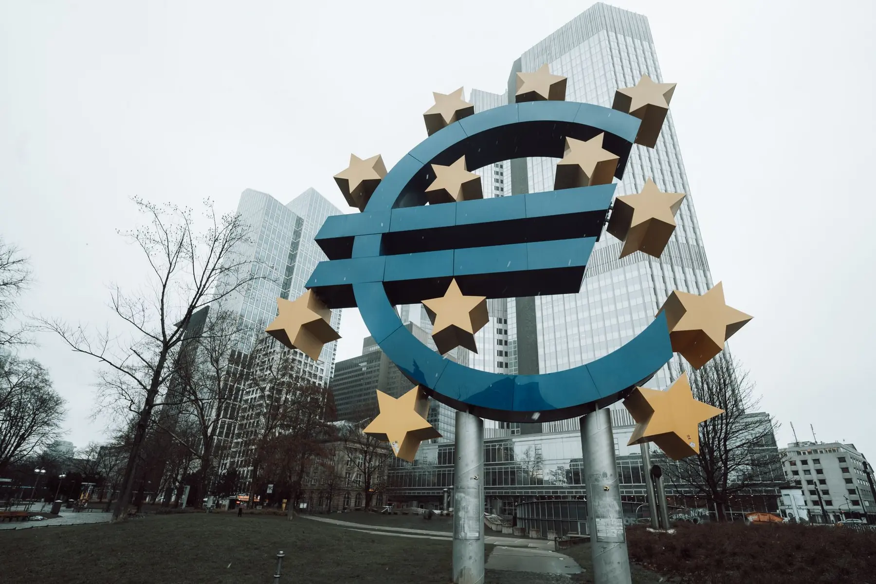 Large blue Euro symbol sculpture with gold stars in front of the European Central Bank buildings in Frankfurt
