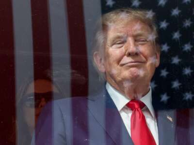 An American flag is reflected off bulletproof glass as U.S. President Donald Trump watches the end of the NTT INDYCAR Series on August 23, 2026 in Washington, D.C.