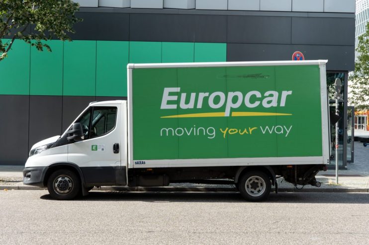 White Europcar moving truck with green side panel and moving your way slogan parked on a street.