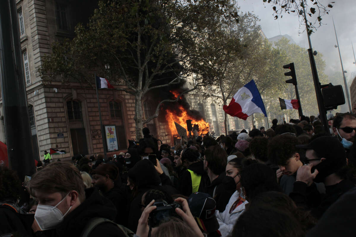An advertisement kiosk is set on fire during student and cost-of-living protests at Place de la République in Paris, France, on October 17, 2026.