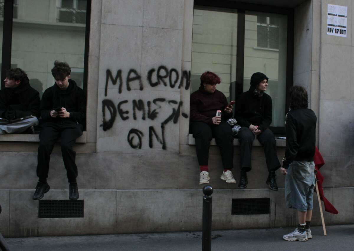 Demonstrators for student and cost-of living-protests gather in Paris, France, on October 17, 2026. A tag on the wall reads “Macron démission” or “Macron, resign.”