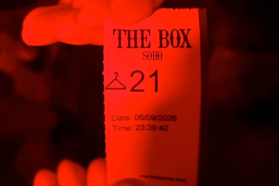 The Box Soho coat check ticket with number 21 and date 05/09/2026, illuminated in red light